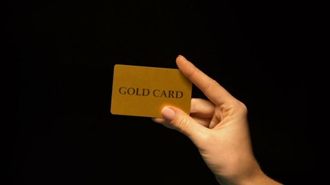 Hand showing gold card on black background, status vip, unlimited finances