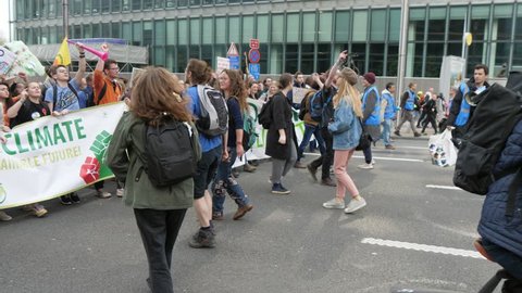Brussels, Belgium - March 30, 2019:Optimistic view of thousands of young people with a wide banner Student 4 climate marching, chanting and dancing in a street in Belgium in spring
