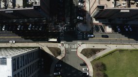Cars Pass Through Intersection As Pedestrians Walk And Play In Park, Aerial Drone Footage
