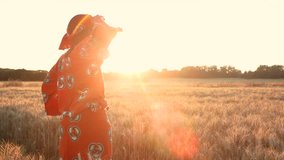 HD Video clip of African woman farmer in traditional clothes standing in a farm field of crops in Africa at sunset or sunrise