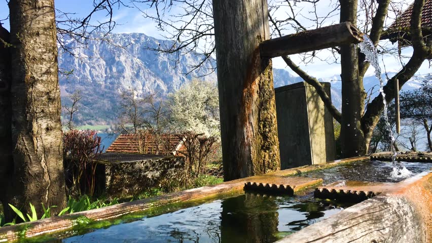 water from wood fountain flowing in beautiful nature with mountains landscape