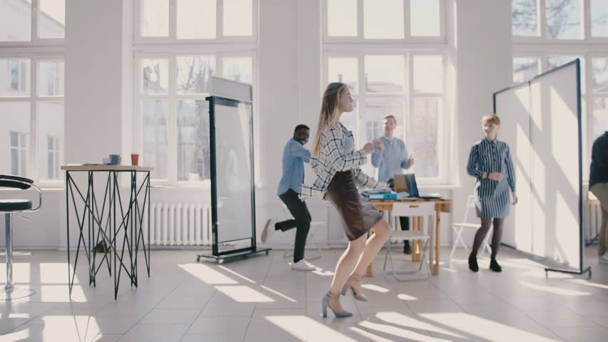 Young happy Caucasian female boss dancing in modern office celebrating together with multiethnic colleagues slow motion. | Shutterstock HD Video #1027315478