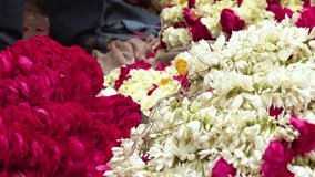 Indian man holding up garlands of brightly colored flowers in a flower market near Ganga river, Varanasi, India, 4k footage video