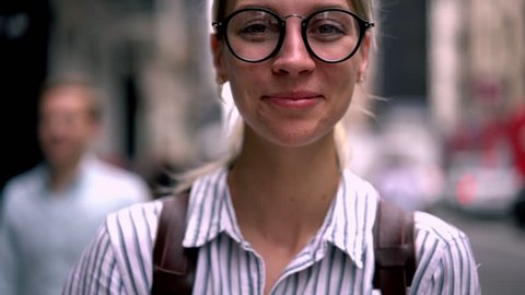 Closeup portrait of sincerely happy caucasian hipster girl with beautiful eyes in eyewear smiling for camera. laughing female using mobile phone application while standing outdoors on city street