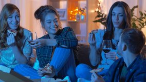 friendship, food and leisure concept - happy friends eating pizza and drinking non-alcoholic wine and watching tv at home in evening - Powered by Shutterstock - Get 15% off with code: PIKWIZARD15