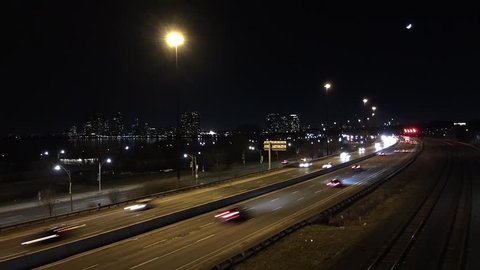 Video footage timelapse of cars driving on a busy city street road highway freeway filmed from a bridge at night. View from above, aerial view. Gardiner expressway, Toronto, Canada.