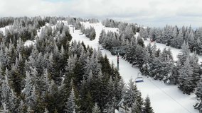 Ski lift in mountain ski resort. Recreational skiing and snowbording. Drone video, aerial view. Winter landscape.