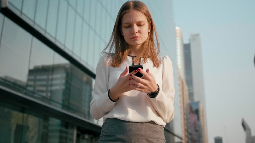 Adult Caucasian Confident Young Business Woman in White Shirt is Talking on Phone Outside near Modern Office Building. Medium Long Low Angle 4K Slow Motion Corporate Shot with Moving Around 360 Camera | Shutterstock HD Video #1027338185