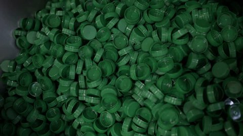 Green plastic bottle caps. Plastic waste. Packaging equipment at dairy factory