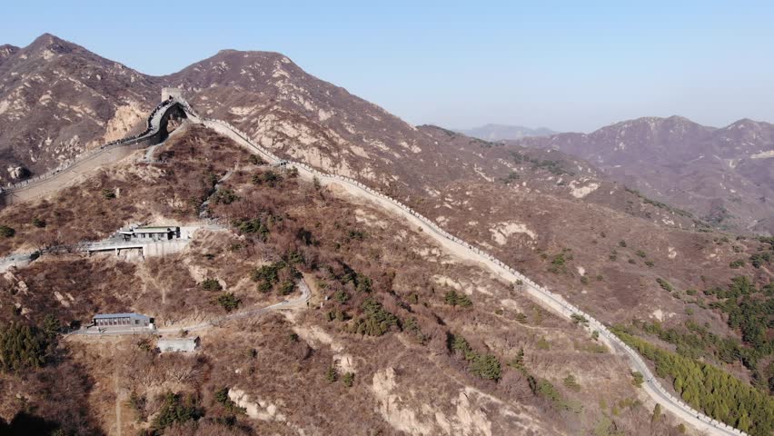 Great Wall of China running up at mountain topped with tower, aerial view of Badaling site. Steep part against beautiful mountainous landscape on background, camera fly forward