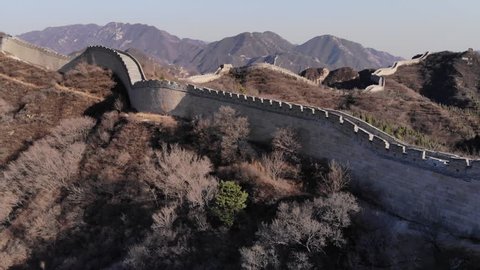 Great Wall of China running up and down on hills, aerial shot of Badaling site. Famous Chinese landmark at Yanqing District of Beijing metropolis, shot at early spring time, bare trees and bushes