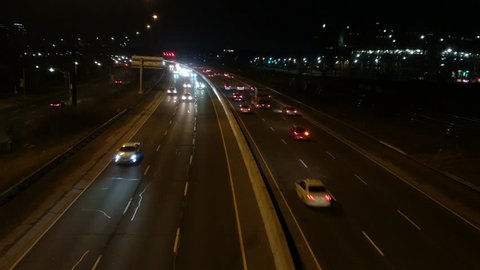 Video footage filmed from a bridge of vehicles cars driving and traffic moving  on busy city road street highway freeway at night. View from above, Gardiner expressway / QEW, Toronto, Canada.