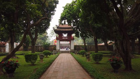 Gimbal forward Temple of Literature Hanoi Vietnam. Ancient historical old complex. Confucius Religious Culture National architecture feature. Tropical park trees. Sight Travel. tourists watch walk