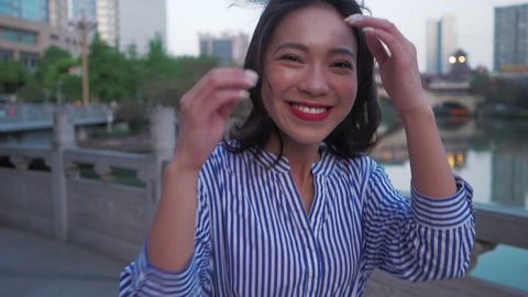 Slow motion of happy young Asian woman running and turn round smile at camera by the riverside at Jiuyanqiao Chengdu City of China Young Asian woman girlfriend enjoy good time with boyfriend traveling