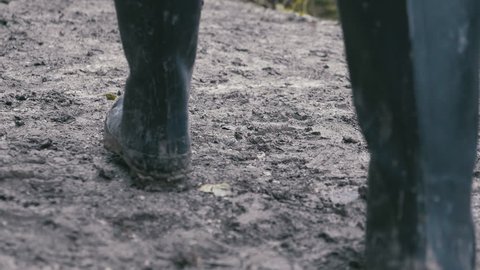 Muddy boots walking along a muddy path, rear view