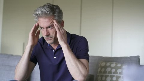 Mature man with pounding headache at home 