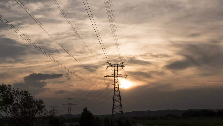 Timelapse in front of high voltage electric pylon, with clouds at sunset