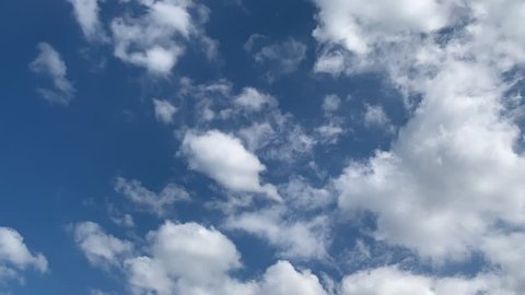 White clouds move rapidly across the blue sky. Fast motion. Time lapse.