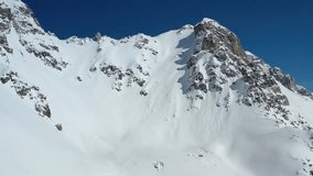 Beautiful aerial view on a massive mountain covered in powder snow with a man climbing it, 4k, Go Everywhere