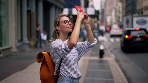 Millennial hipster girl tourist in casual outfit photographing buildings architecture and in New York using camera and application on modern cellular phone, slow motion effect. Female wanderlust 