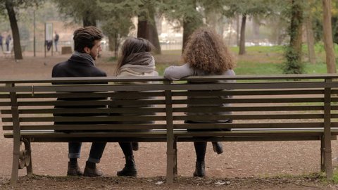 betrayal, cheating.Three people on the bench man flirting with both women