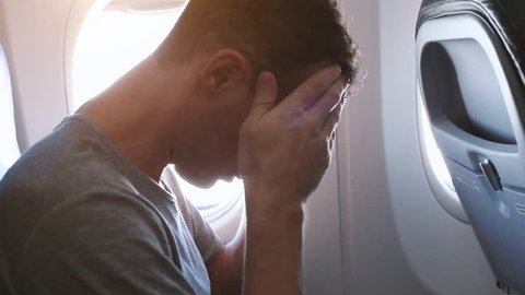 headache in the airplane, man passenger afraid and feeling bad and sick during the flight in plane, aerophobia