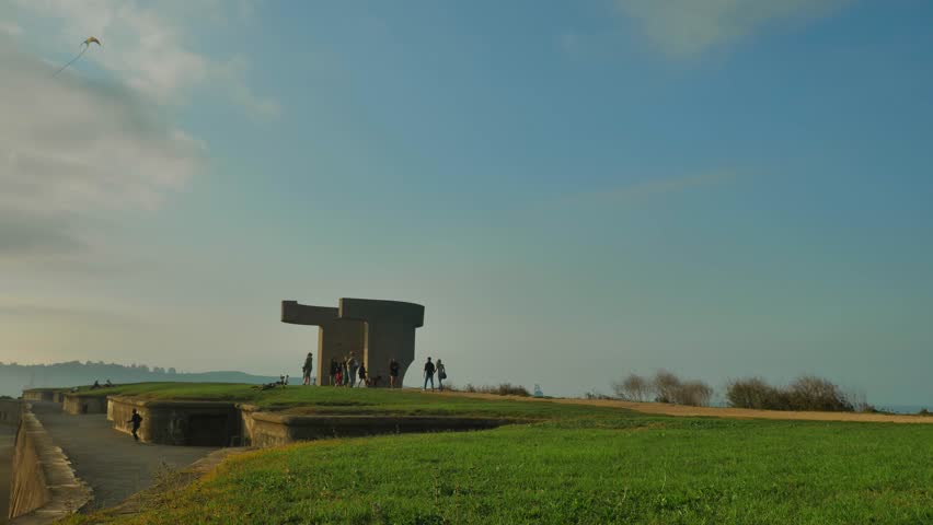 A distant wide shot of people strolling near a road and grass fields.