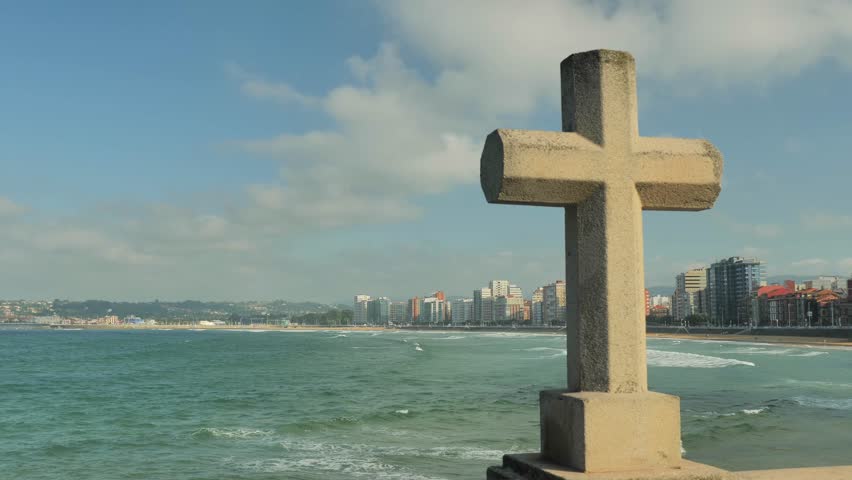 A stone cross facing the sea in Gijon (Asturias, Spain), slow truck shot. Taken in August 2018.