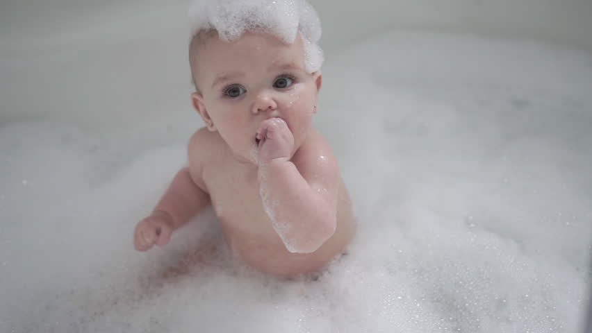 A Baby girl bathes in a bath with foam and soap bubbles | Shutterstock HD Video #1027391069