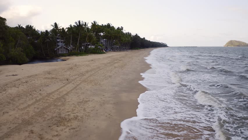Aerial, beautiful view on a beach of Palm Cove, right above the ocean waves in Cairns, Queensland, Australia