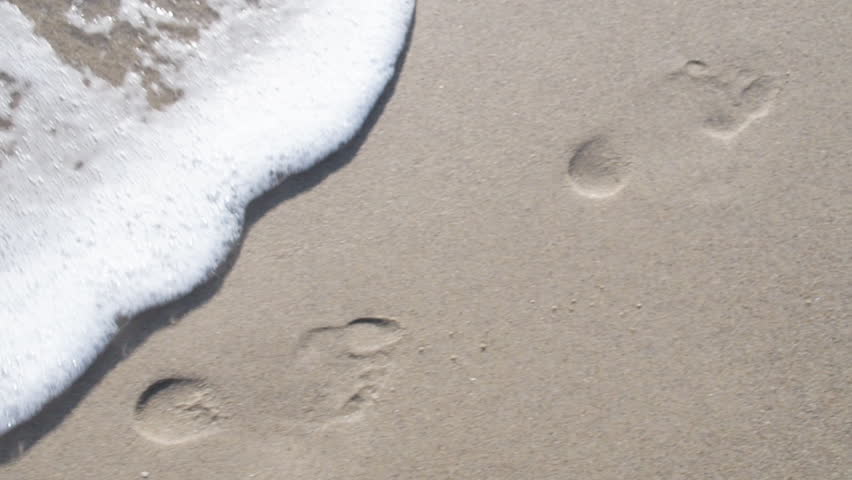Footprints in the sand. The sea washes away footprints in the sand. | Shutterstock HD Video #1027410113