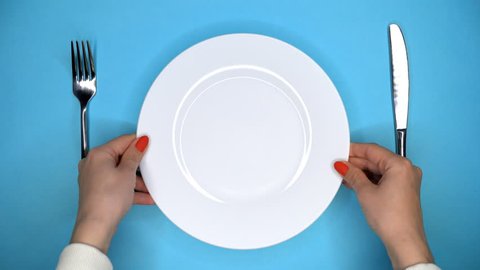 Table setting in restaurant or cafe. Fork and knife. Female hands puts and takes away white plate from blue table