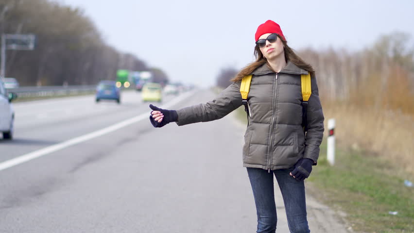 Hitchhiking young adult man hitchhiker waiting pointing thumb up on ...