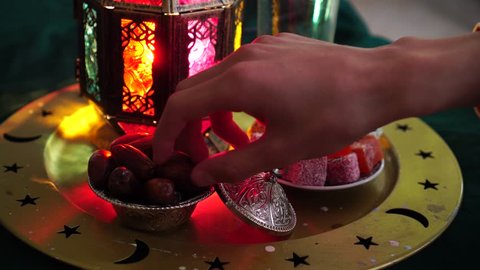 The Food of Ramadan. Glass of water, dates, dried fruits, sweets. A man eats dates to break the fast 