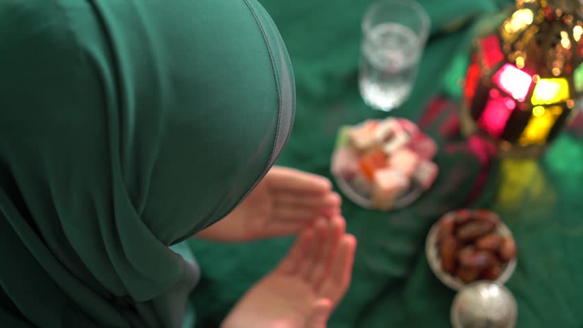 Muslim woman wearing hijab. Holy month of Ramadan. Dua (prayer) for breaking fast and beginning fast. Food and water. Praying, Islam, Religion. Hari Raya Aidilfitri Holiday