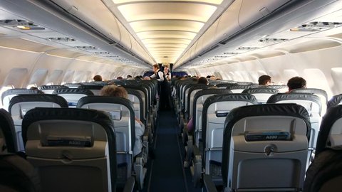 GERMANY - 2019: Onboard a flight with people sitting on the aircraft and attendants in the aisle