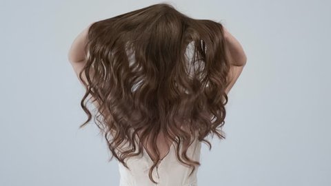 Woman moves long hair. Rear view. Girl shakes long straight hair. Female model is fluttering hair. Slow motion footage. Rear view