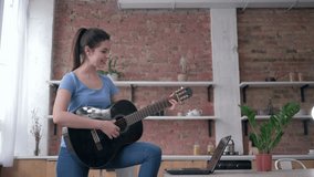 musical education, happy beautiful guitarist girl learning play stringed musical instrument uses laptop computer with online video lesson and enjoy music at home