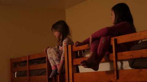 Little kids listen to grandpa tell a story while sitting in bunkbeds in a large room during a sleep over