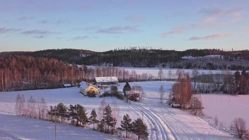 Aerial rural landscape of winter house next to a frozen lake and sun