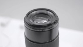 Close-up of new telephoto lens for digital cameras and mirror less system on a showcase on exhibition. Black telephoto lens on white background.