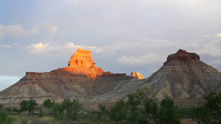 A time-lapse of beautiful rain clouds moving over a sandstone desert butte at sunset in the desert of Southern Utah