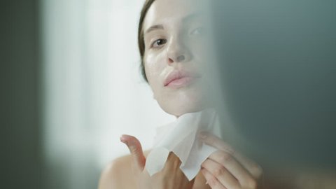 Close up of woman rubbing moisturizer on face with washcloth in mirror / Cedar Hills, Utah, United States