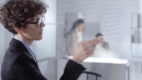 Close up of intelligent businesswoman tapping on invisible multi-touch interface on glass wall and reading on virtual screen in office. Video suitable for adding AR graphics