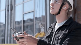 Man architect controlling flying drone for aerial view. Portrait of a successful engineer, builder using smartphone to control the quadcopter. Modern technologies in construction, and architecture