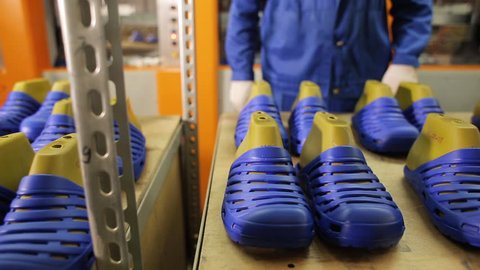 Worker puts on just made rubber slippers on the pads. Shoe manufacturing. A shoe factory worker folds shoes on a production line. Shoe factory. Rubber slippers at the factory.