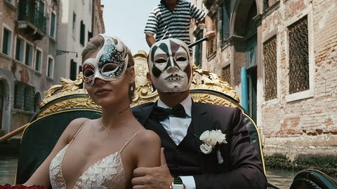 Traditional Venetian Mask. Newlyweds On A Gondola In Masks. Romantic Young Beautiful Couple Sailing In Venetian Canal In Gondola. Italy, Europe.