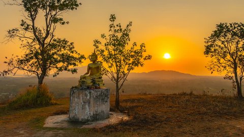 timelapse scenery sunset behind the bell and golden Buddha statue on hilltop of Baan Ngao temple Rarong province Thailand. 