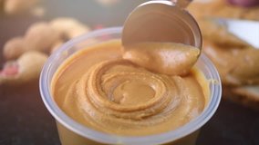 Peanut butter. Person making sandwiches with Creamy smooth peanut butter. Jar on a table. Natural nutrition and organic food. American cuisine. 4K UHD video, slow motion