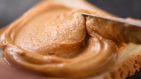 Peanut butter. Person making sandwiches with Creamy smooth peanut butter. Bread and peanut butter on a table. Natural nutrition and organic food. American cuisine. 4K UHD video, slow motion